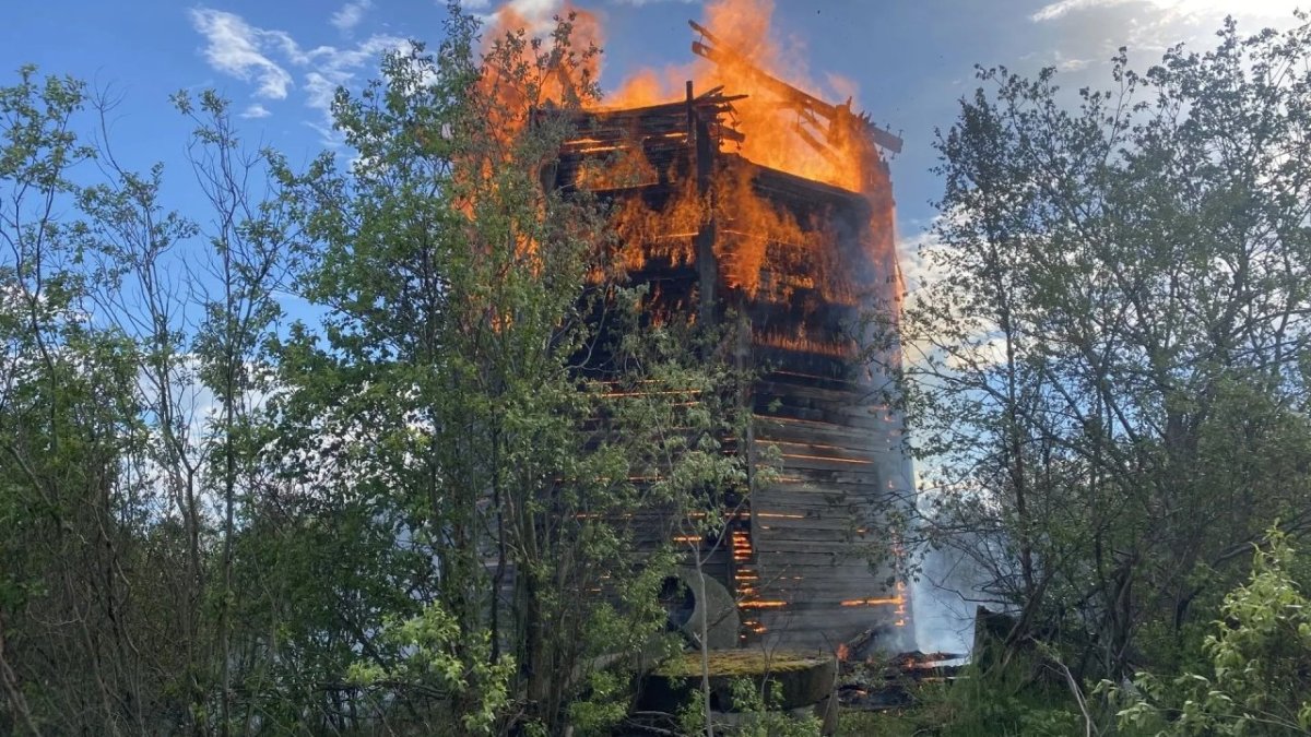 Горит сильным пламенем деревянная водонапорная башя летом