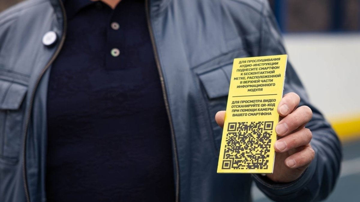 Мужчина держит в руках табличку с QR-кодом