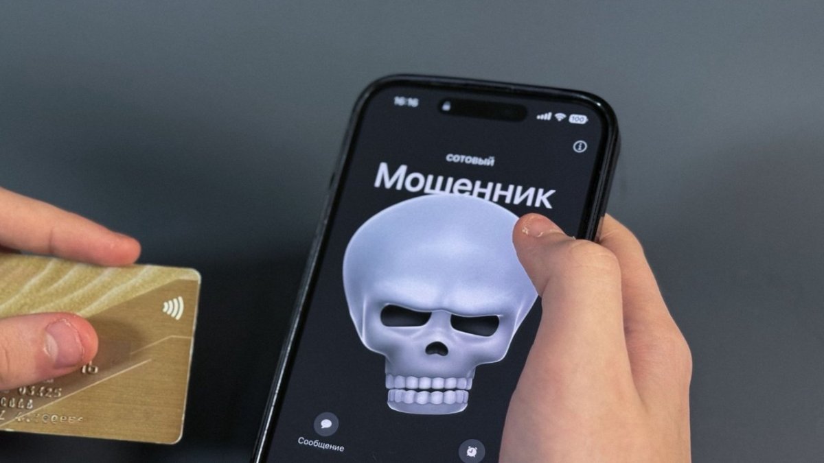 Человек держит в руках мобильный телефон и банковскую карту.