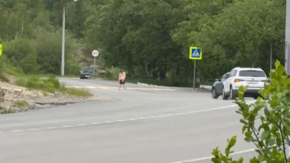 Мужчина в черных шортах и с голоенным торсом стоит посреди дороги