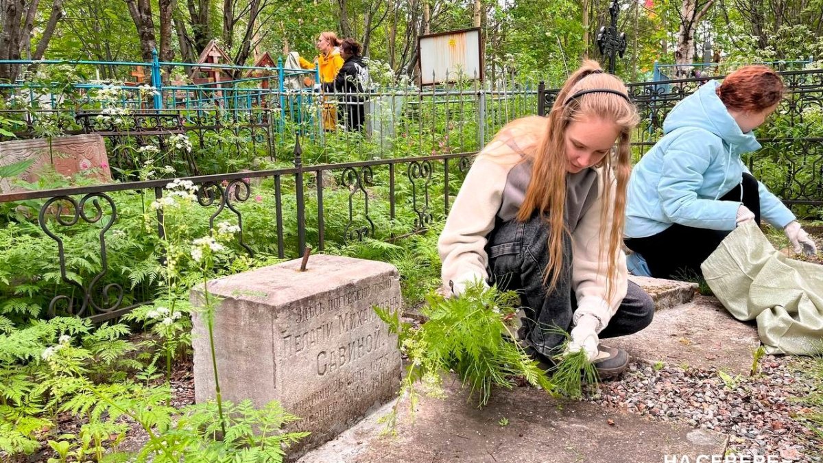Девушка сидит на корточках и прибирается на старинной могиле