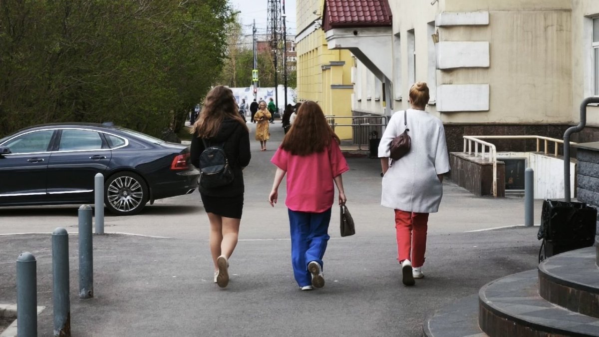 Три девушки идут по дороге в городе летом