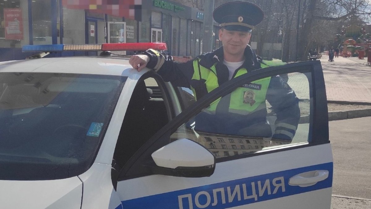 Сотрудник ГИБДД стоит у открытой двери служебной машины