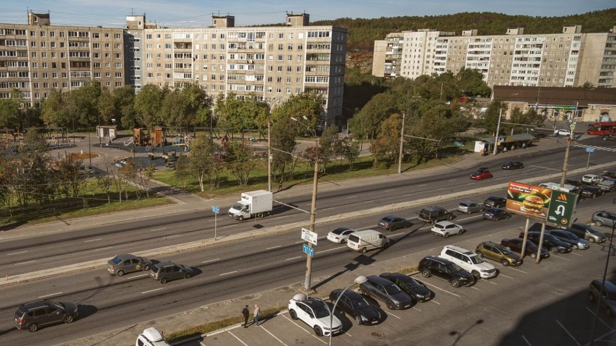 Машины стоят на парковке возле дороги и остановки