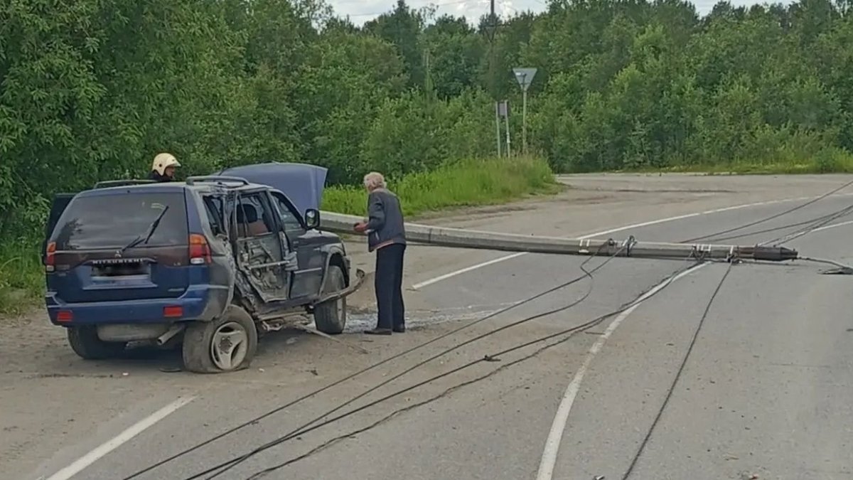 Стоит покареженная машина на дороге и лежит столб освещения