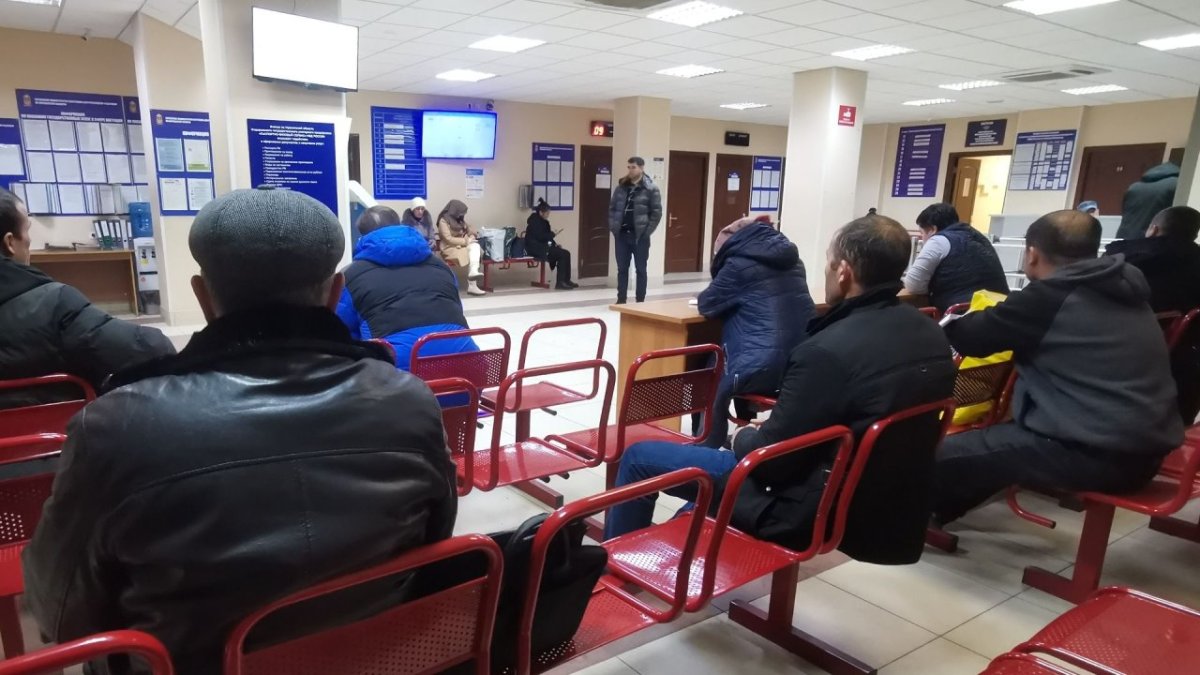 Посетители сидят на стульях в зале ожидания отделения миграционной службы