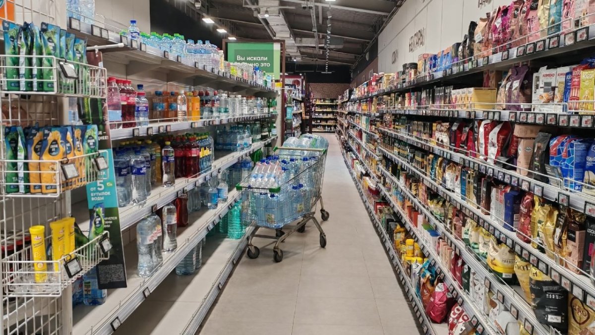В Магазине тележка стоит среди полок с различными товарами