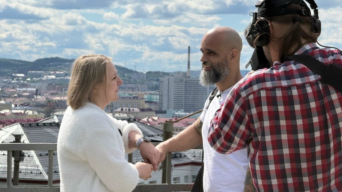 Мужчина и женщина смотрят друг на друга и улыбаются пока оператор снимает их на камеру