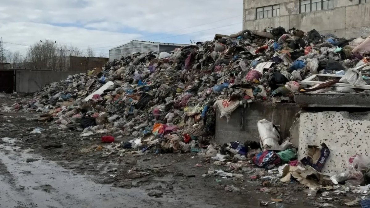 Различный мусор лежит в огромной куче на земле рядом со зданием