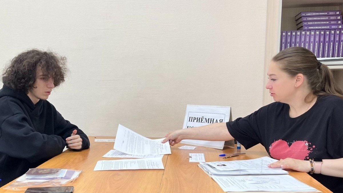 Молодой чеовек сидит за столом напротив женщины средних лет