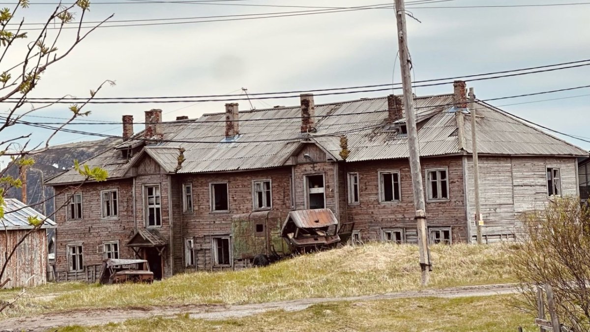 Старый заброшенный деревянный дом на фоне травы летом