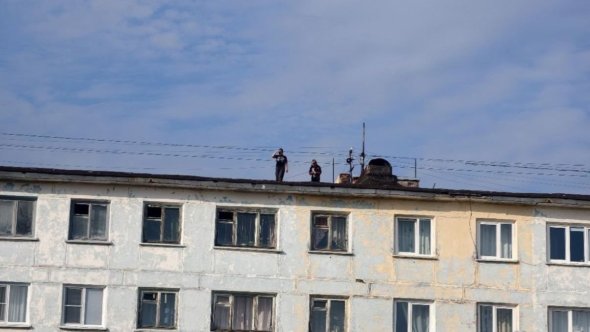 Двое дете ходят по крыше жилого пятиэтажного дома летом