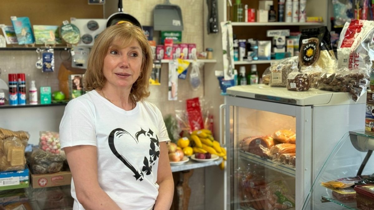 Женщина стоит на фоне прилавков с продуктами в магазине