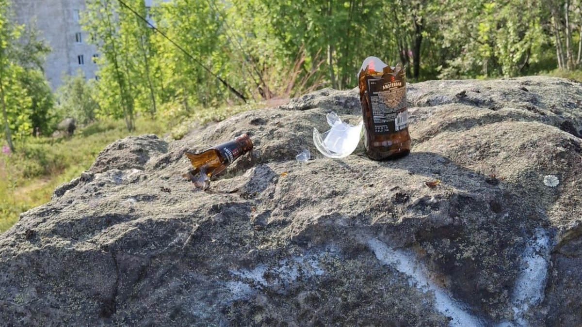 Разбитые стеклянные бутылки лежат на камне летом