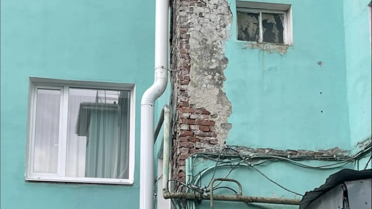 Разрушающийся фасад жилого дома с открытой кирпичной кладкой.