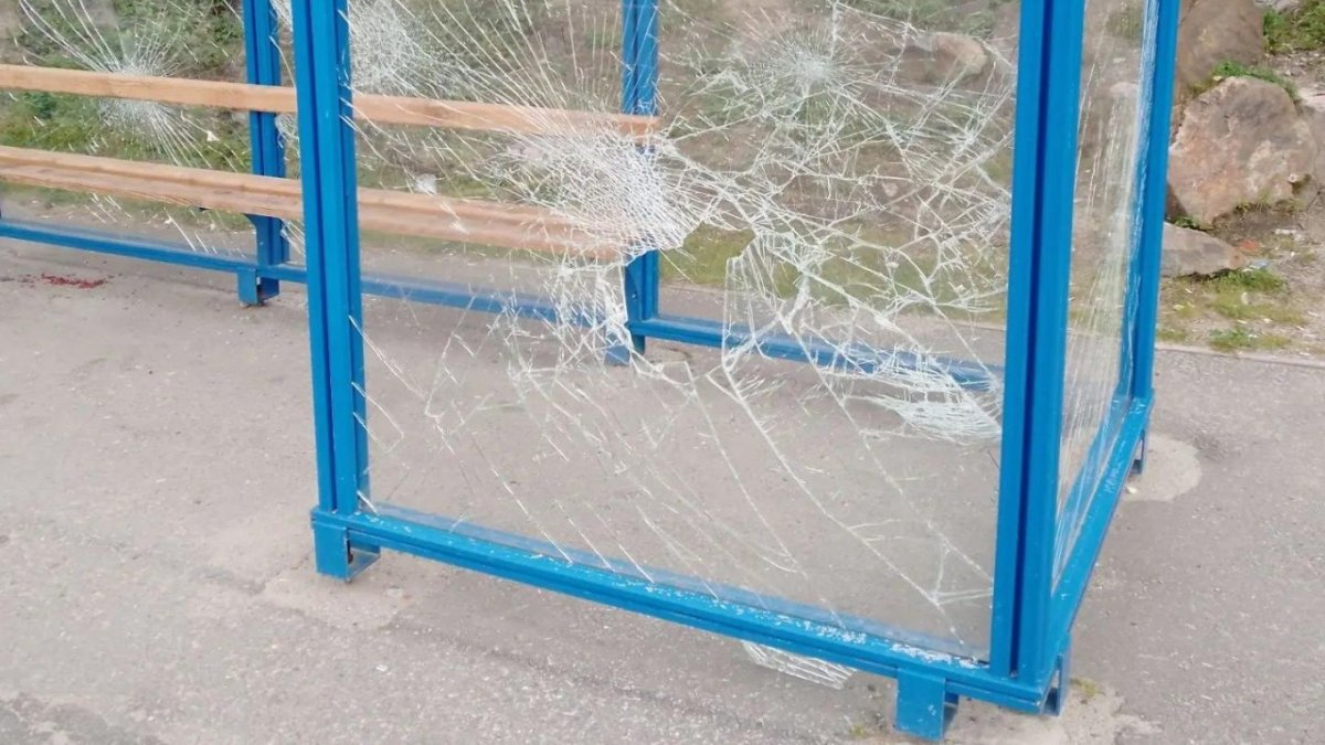 Разбитое стекло остановки общественного транспорта летом в городе.