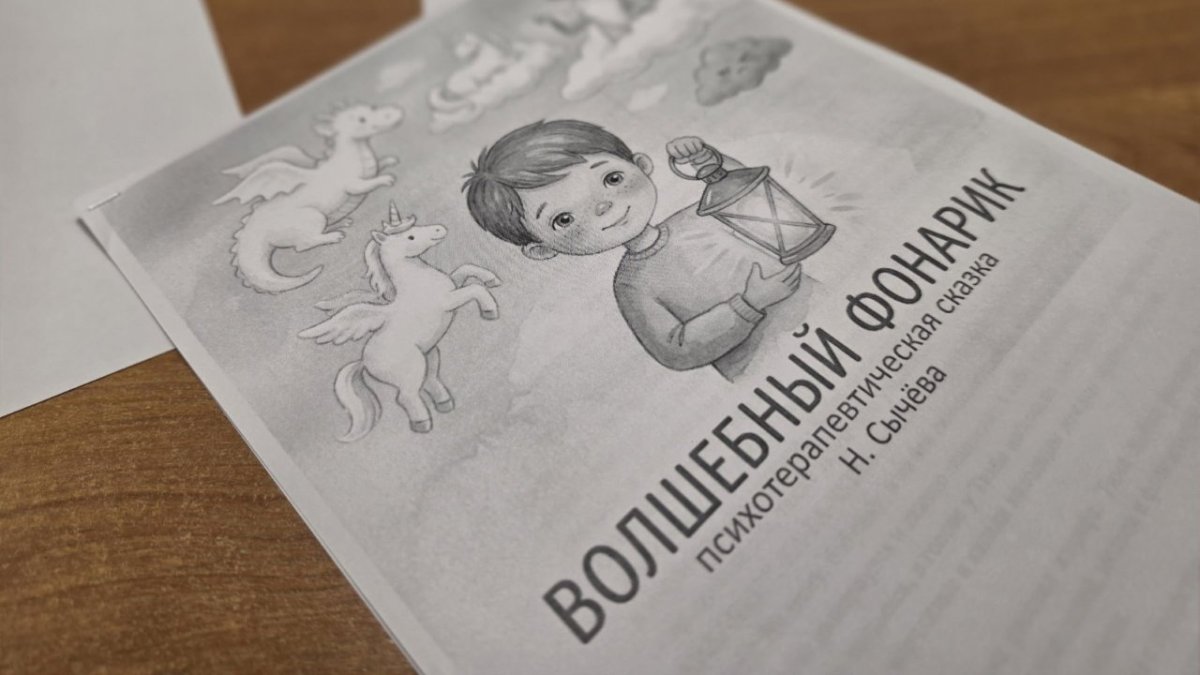 Книжка с черно-белыми рисунками лежит на столе.