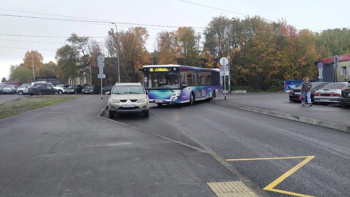 В городе на остановке стоят машины и автобус осенью.
