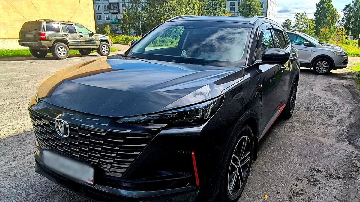 Черная иномарка стоит на улице в городе осенью.