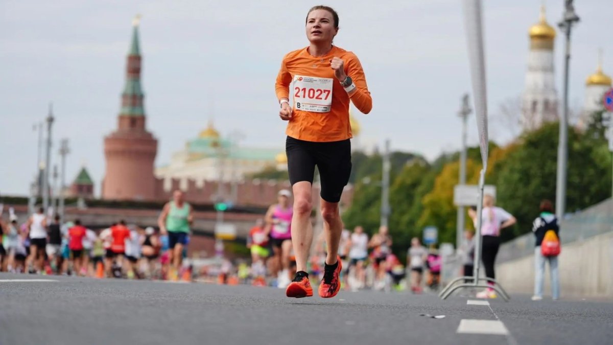 Девушка бежит на фоне Красной площади в Москве.